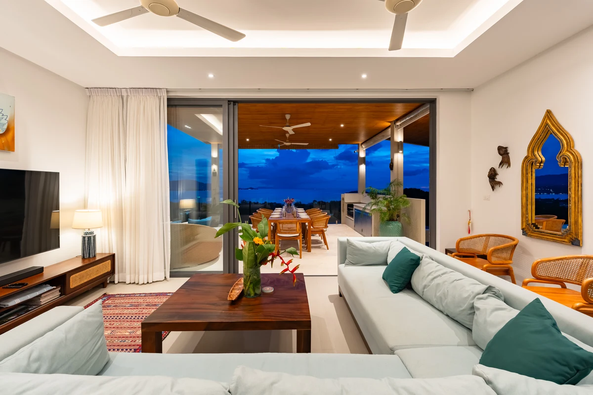 The open living room looking onto the terrace and sea at dusk